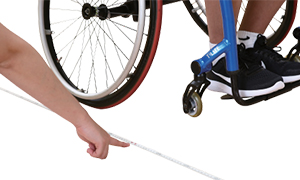 휠체어를 탄 실시자 아래에 줄자가 있고 다른 사람의 팔이 해당 줄자를 가리키고있다.