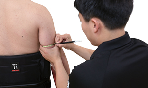 팔 뒷편에 펜으로 표시를 하고있는 검사자